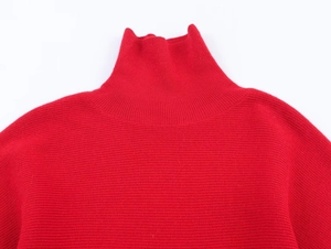 Dettaglio del maglione rosso a dolcevita con trama a coste e morbido tessuto in misto lana