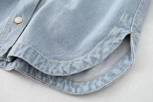 Detailed macro view of denim jacket curved hem with side slit and silver button