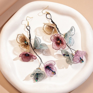 Macro shot of long floral embroidery tassel earrings with colorful glass beads detail