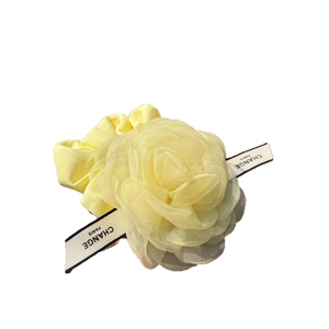 Yellow organza rose hair flower with lettered ribbon on white background for women