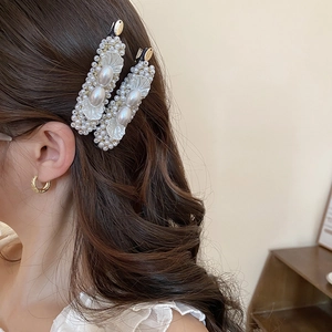 Detail of elegant pearl hair clips and gold textured hoop earrings worn by a model