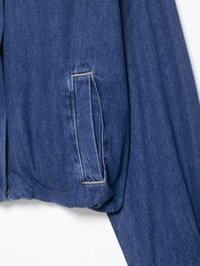 Detail view of deep blue denim jacket showing side pocket and contrast stitching texture
