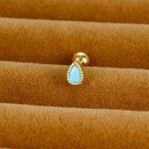 Détail macro de la boucle d'oreille goutte turquoise avec bordure perlée dorée