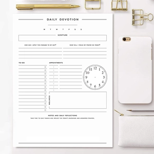 Flat lay of daily prayer planner with gold pen and phone in minimalist desk setting