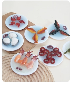 Miniatuur zeevruchtenmodellen zoals garnalen en vis op ijzige witte kleine borden