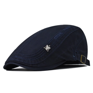 Detail of navy cotton flat cap with silver bird emblem and adjustable metal buckle strap