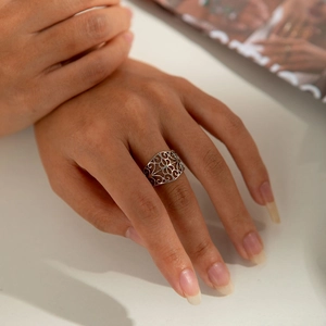 Detail of vintage hollow engraved silver ring on finger with elegant vine pattern