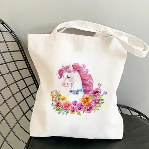 Close-up of white canvas tote bag featuring vibrant unicorn and floral art illustration