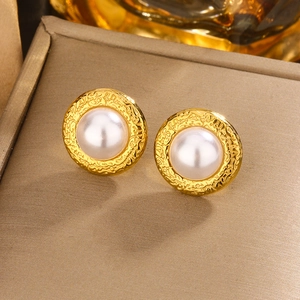 Macro shot of French vintage pearl stud earrings with textured gold metal frame