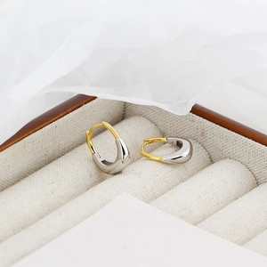 Macro di orecchini a forma di U bicolore esposti in una elegante confezione regalo per gioielli