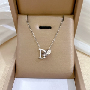 Macro shot of silver titanium steel D-letter pendant necklace with crystal ring on box