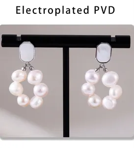 Macro view of PVD electroplated drop earrings with white pearls and geometric studs