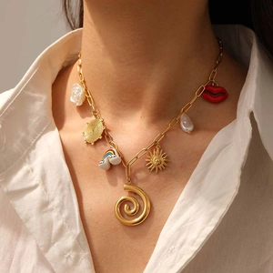 Golden multi-pendant chain necklace with rainbow, sun, and lip charms on a white shirt
