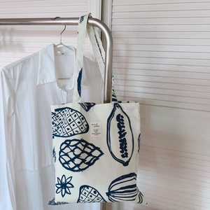 Détail du sac fourre-tout en toile crème avec imprimé floral bleu marine et étiquette tissu