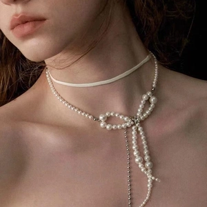 Elegant double-layered pearl necklace featuring a bow pendant and long chain tassels