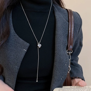Close-up of heart-shaped silver pendant necklace worn over a black turtleneck top
