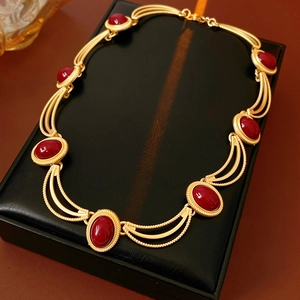 Detailed shot of vintage gold twisted rope necklace with oval red gemstones in jewelry box
