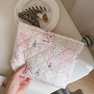 Detailed shot of quilted floral cotton makeup bag featuring cute rabbit illustrations