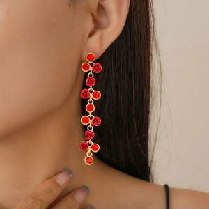 Gros plan de boucles d'oreilles pendantes en or avec roses rouges et strass brillants