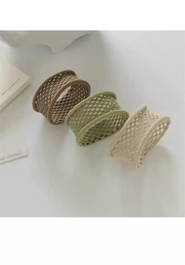 Détail d'élastiques à cheveux tressés en marron, vert sauge et beige sur un bureau