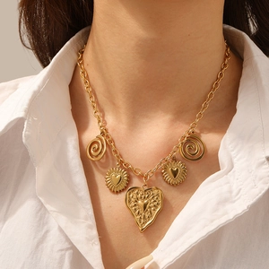 Gold stainless steel necklace with relief heart and spiral pendants on a female model