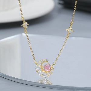 Close-up of gold moon necklace featuring pink heart stone and sparkling zircon accents