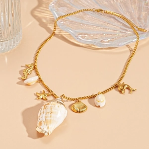 Detailed shot of gold necklace with sea star, seahorse, and natural conch shell pendants