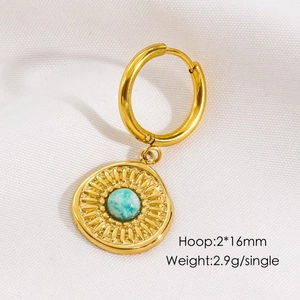 Detailed macro view of gold hoop earring with turquoise stone sunburst charm