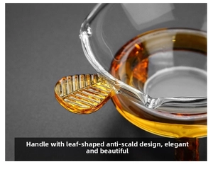 Macro view of a clear glass tea strainer with an amber leaf handle and golden tea