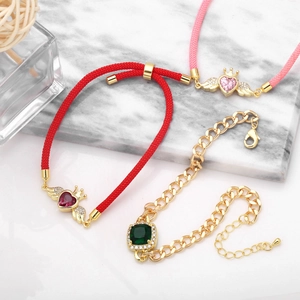 Dettaglio di braccialetti vintage a cuore e corona con gemme colorate su marmo bianco