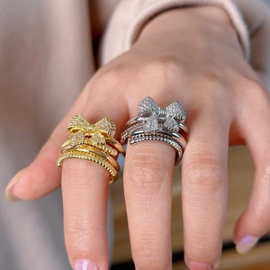 Elegant gold and silver bow rings with sparkling zircon crystals on model fingers