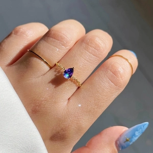 Détail d'une pierre violette en forme de goutte sur bague chaîne dorée à l'or 18k