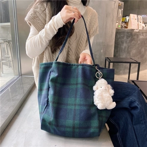 Detail of green and blue checkered wool tote bag with a cute white plush lamb pendant