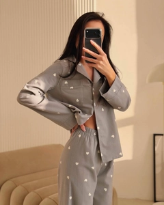 Detail of grey pajama set with white heart print, featuring lapel buttons and cotton fabric