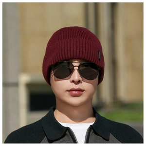 Detail of burgundy ribbed knit beanie showing soft texture and folded brim on a model