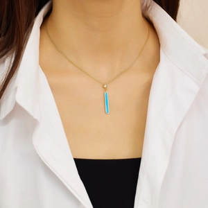 Detalle de un collar de oro con colgante rectangular de esmalte turquesa y pequeño diamante
