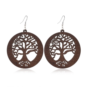 Macro detail of round hollow wood earrings with Tree of Life engraving and silver hooks