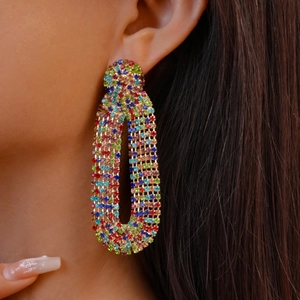 Close-up of model wearing geometric drop earrings with vibrant multi-color zircons