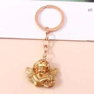 Macro detail of golden metal angel keychain holding a harp with wings on a pastel background