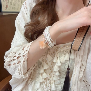 Detail of layered bohemian bead bracelet with pink crystals and decorative tassel on wrist