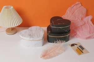 Detailed view of heart-shaped marble gift boxes with gold trim and feather accents