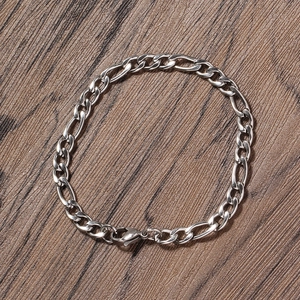 Detail view of silver 5mm Figaro link bracelet with lobster clasp on dark wood