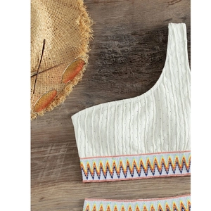 Close-up of white one-shoulder bikini top with texture and colorful wave band