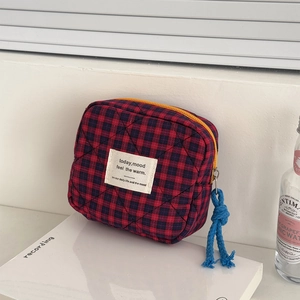 Detail of red and blue checkered quilted pouch with contrast yellow zipper and blue cord