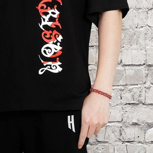 Detail of red and silver industrial chain bracelet on a male model wearing black streetwear