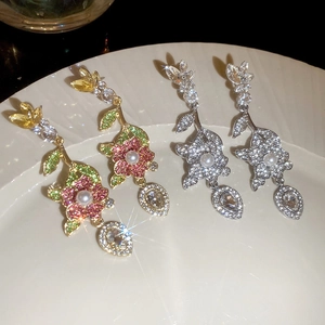 Dettaglio di orecchini floreali scintillanti con strass e perle su vassoio in ceramica