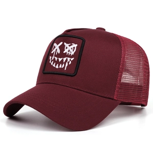 Detail of burgundy trucker hat with mesh back and embroidered face patch on the front