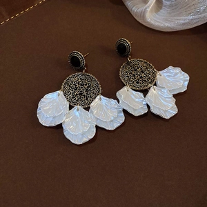 Close-up of bohemian tassel earrings with shell petals and hollow golden mandala discs