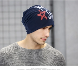 Detail view of a navy blue knit beanie featuring a red star and rock star print texture