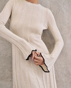 Détail de la texture en maille et du passepoil noir contrasté sur la manche de robe beige